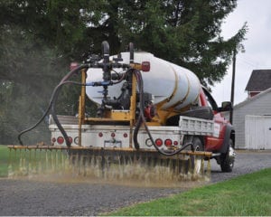 Dustkill truck distributing treatment formula to a gravel road.